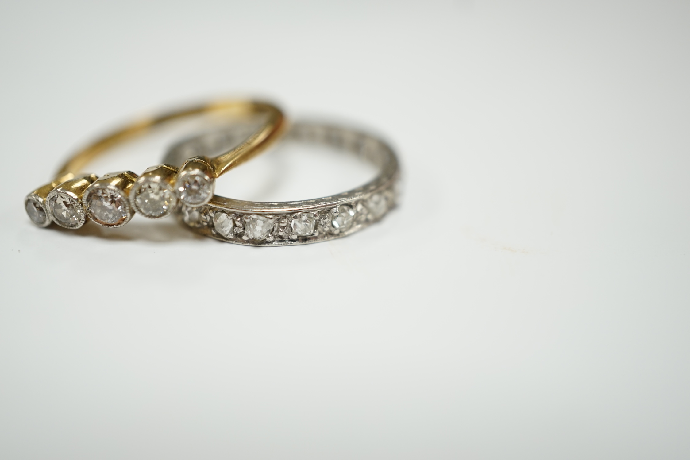 A white metal and diamond chip set full eternity ring, size L and an 18ct and graduated five stone diamond set ring, size M.